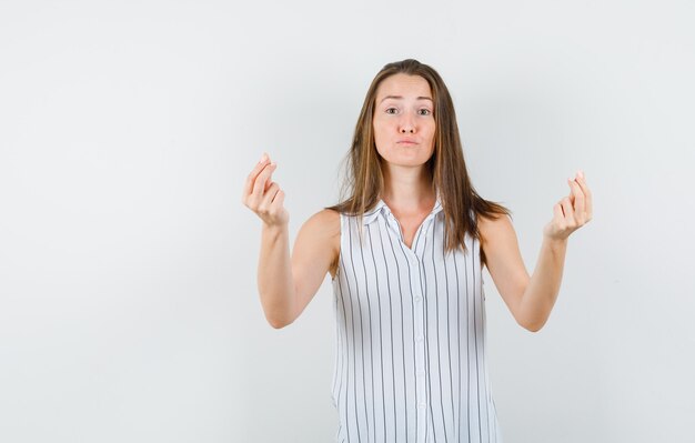 Jonge vrouw in t-shirt gebaren met handen en vingers en hulpeloos, vooraanzicht op zoek.