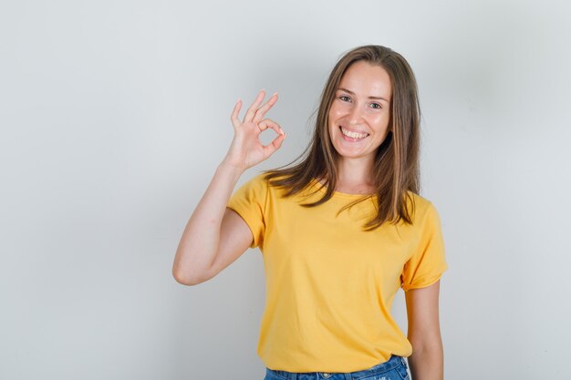 Jonge vrouw in t-shirt, korte broek die en ok teken glimlachen toont