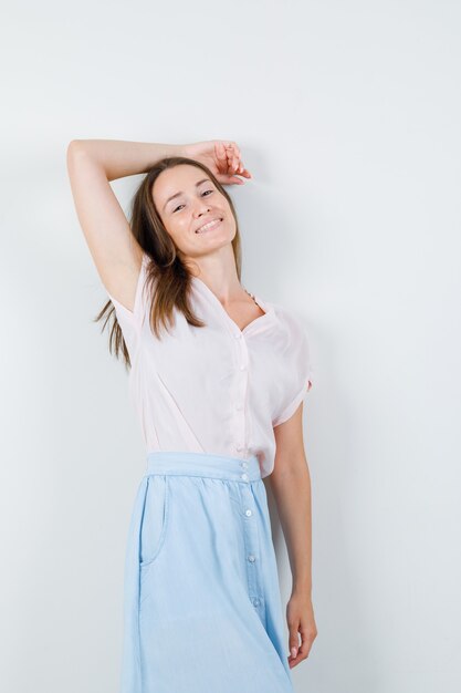 Jonge vrouw in t-shirt, rok poseren terwijl staande en op zoek glamoureus, vooraanzicht.