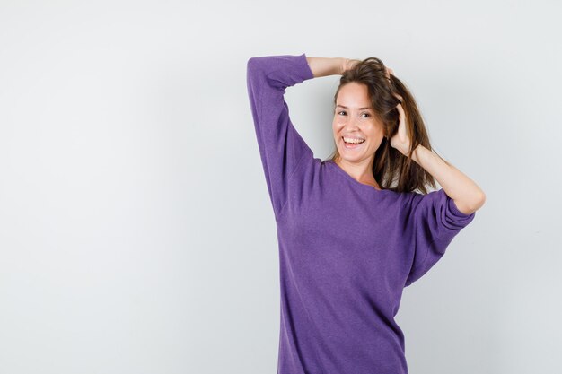 Jonge vrouw in violet overhemd met streng met handen en op zoek vrolijk, vooraanzicht.