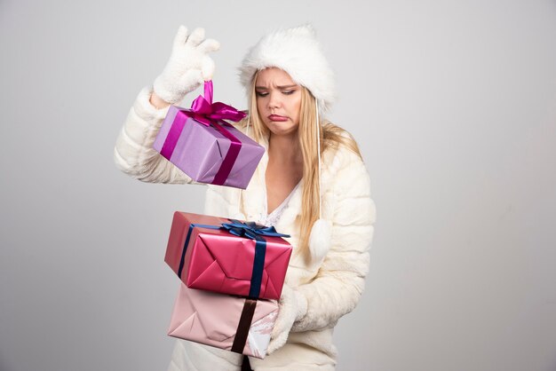 Jonge vrouw in winteroutfit die helaas naar geschenkdozen kijkt.