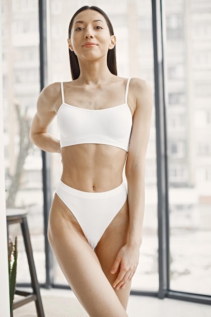 Jonge vrouw in wit ondergoed poseren in studio met grote ramen