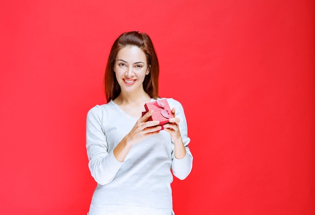 Jonge vrouw in wit overhemd met een kleine rode geschenkdoos