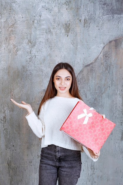 Gratis foto jonge vrouw in wit overhemd met een rode boodschappentas