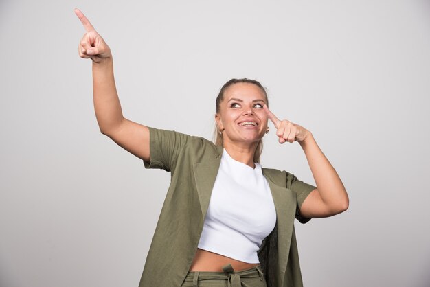 Jonge vrouw in wit overhemd wijzend naar haar zijde.