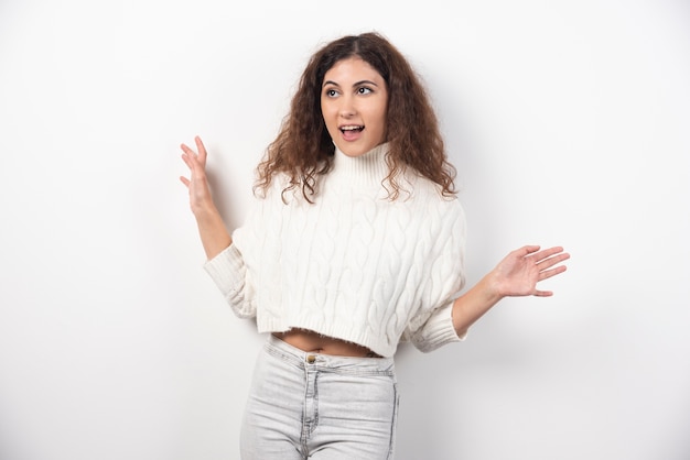 Jonge vrouw in witte trui met krullend haar poseren. Hoge kwaliteit foto