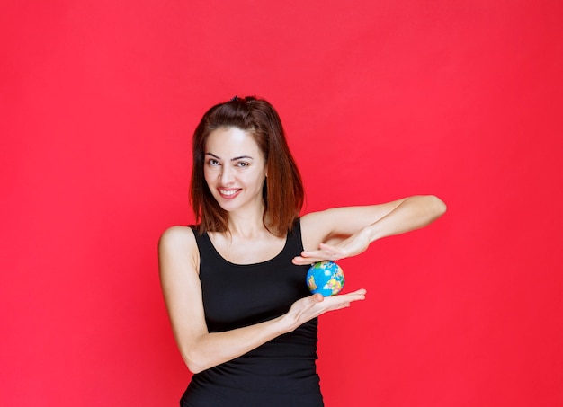 Jonge vrouw in zwart hemd met een mini-wereldbol