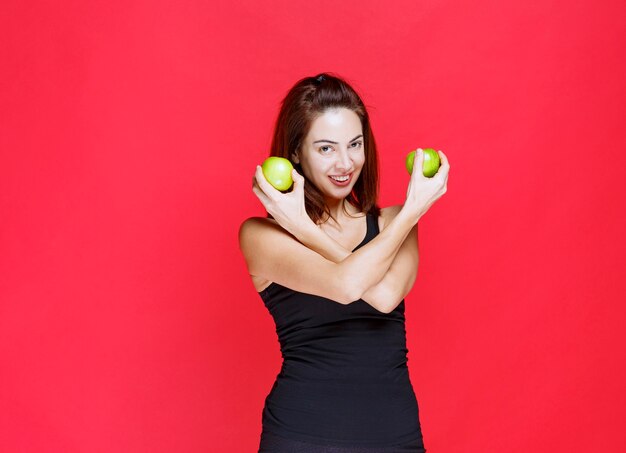 Jonge vrouw in zwart hemd met groene appels