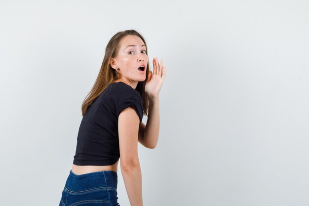 Jonge vrouw in zwarte blouse die iemand belt en gericht kijkt