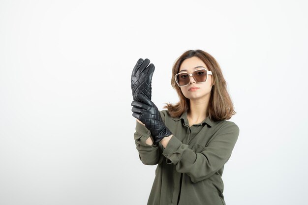 Jonge vrouw in zwarte handschoenen en bril poseren en staan. Hoge kwaliteit foto