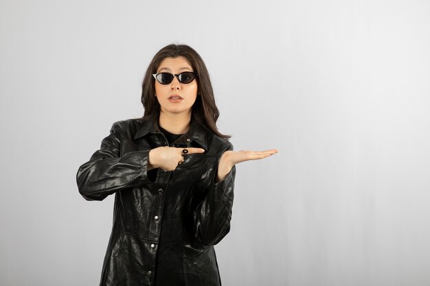 jonge vrouw in zwarte jas dragen van een bril en poseren.