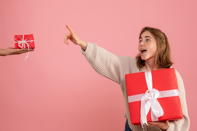 jonge vrouw kerst aanwezig houden en het accepteren van geschenk van man op roze