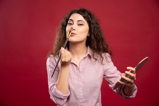 Jonge vrouw kietelt haar neus met een kwast.