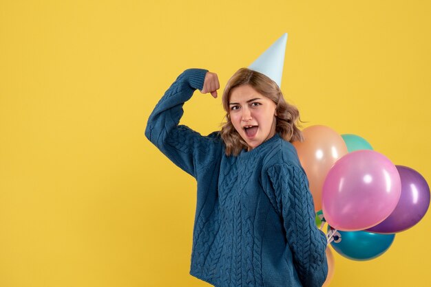 jonge vrouw kleurrijke ballonnen achter haar rug op geel verbergen