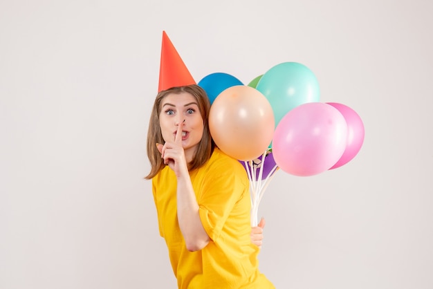Jonge vrouw kleurrijke ballonnen achter haar rug op wit verbergen