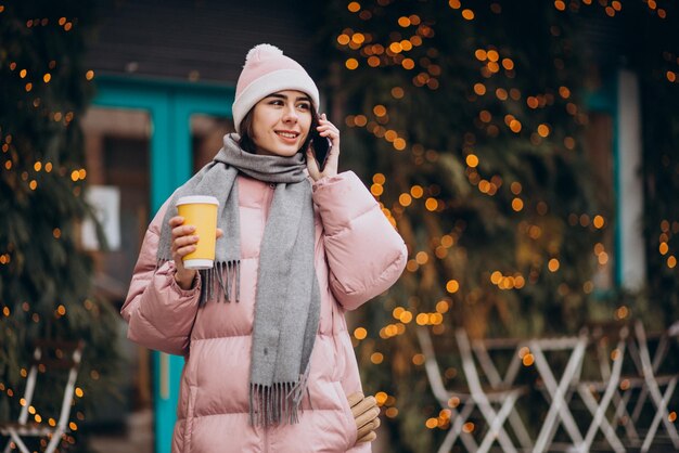 Jonge vrouw koffie drinken en praten aan de telefoon bij het café