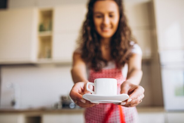 Jonge vrouw koffie drinken in de keuken in de ochtend
