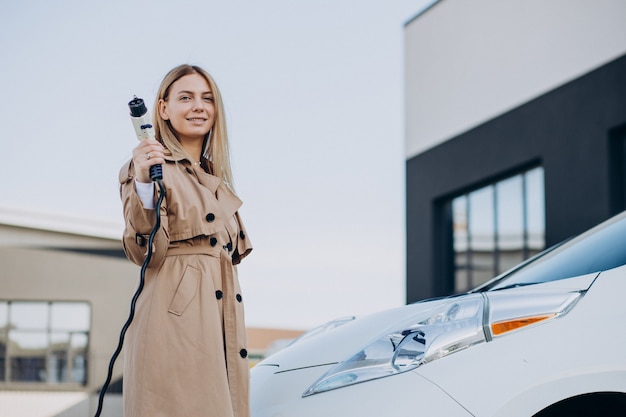 Jonge vrouw laadt haar elektrische auto op met laadpistool