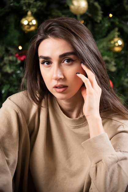 Jonge vrouw liggend op pluizig tapijt in de buurt van kerstboom.