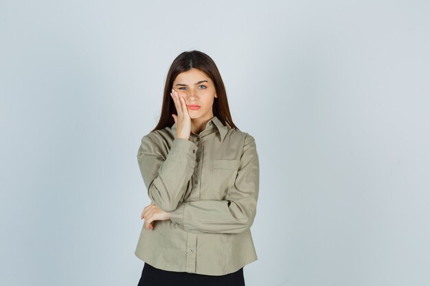 Jonge vrouw lijdt aan kiespijn in shirt, rok en ziet er pijnlijk uit, vooraanzicht.