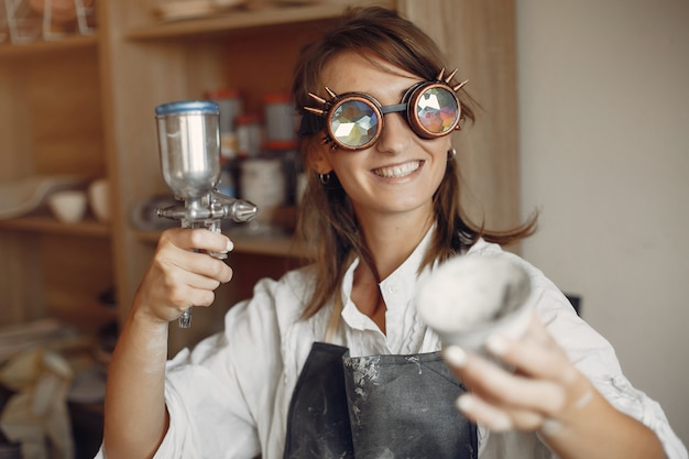 Jonge vrouw maakt aardewerk in werkplaats