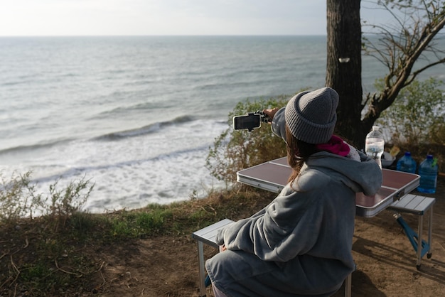 Jonge vrouw maakt een foto op een smartphone van het zeegezicht