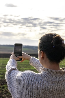 Jonge vrouw maakt een foto van het veld met smartphone