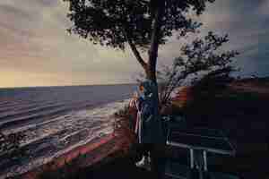 Gratis foto jonge vrouw maakt foto's van de zeezonsondergang met smartphone