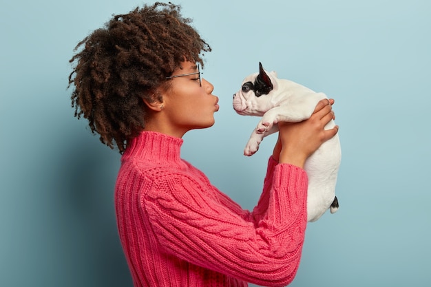 Jonge vrouw met afro kapsel bedrijf puppy