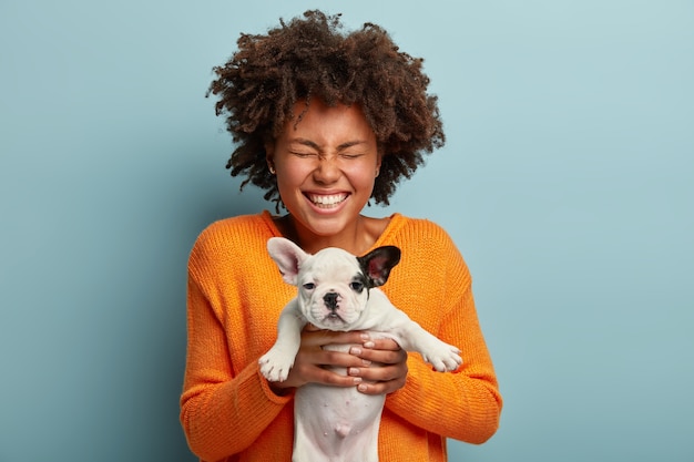 Gratis foto jonge vrouw met afro kapsel bedrijf puppy