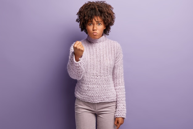 Gratis foto jonge vrouw met afro-kapsel die paarse trui draagt