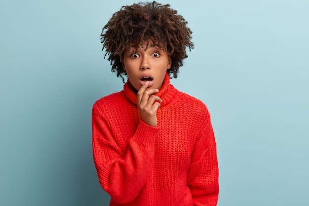 Jonge vrouw met afro-kapsel, gekleed in rode trui