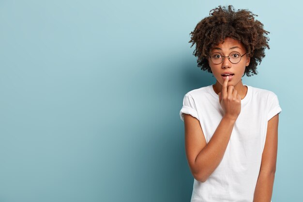 Jonge vrouw met Afro-kapsel, gekleed in wit T-shirt