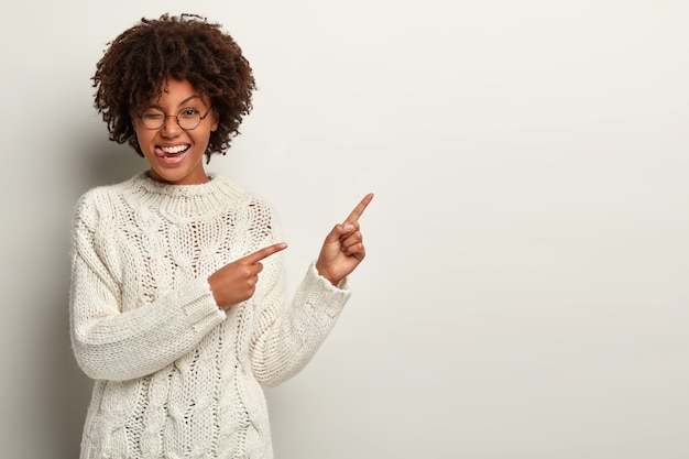 Jonge vrouw met Afro-kapsel, gekleed in witte trui