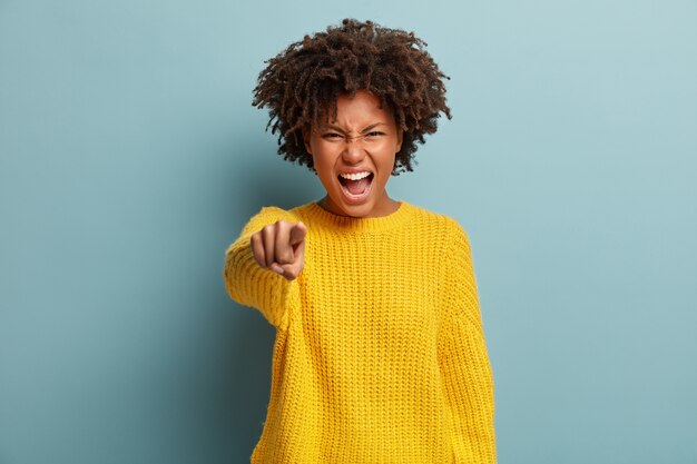 Jonge vrouw met Afro kapsel gele trui dragen