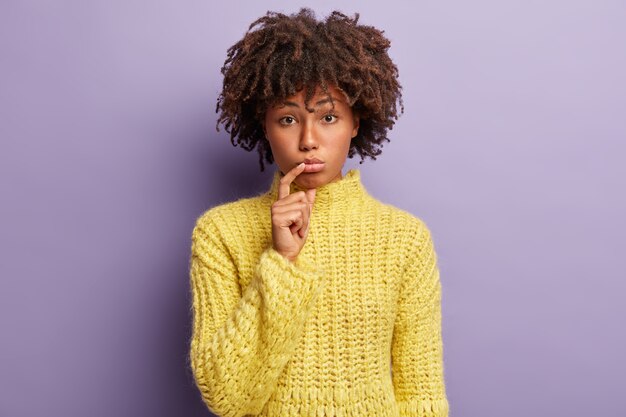 Jonge vrouw met Afro kapsel gele trui dragen