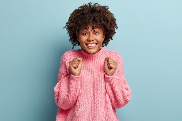 Jonge vrouw met Afro kapsel met roze trui.