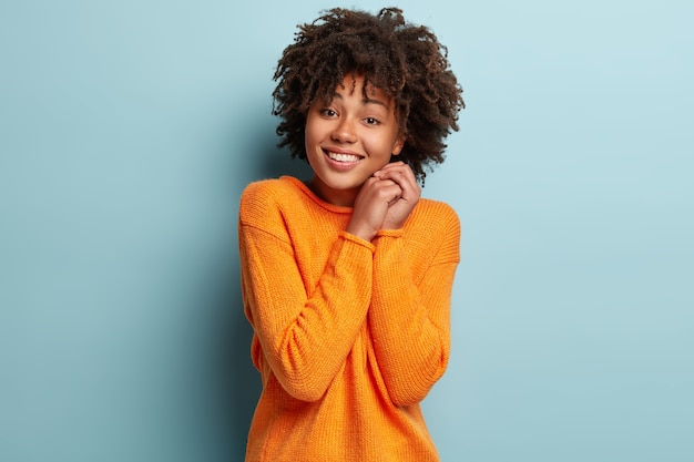 Jonge vrouw met Afro kapsel oranje trui dragen