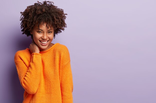 Jonge vrouw met Afro kapsel oranje trui dragen