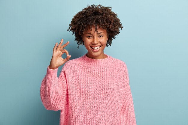 Jonge vrouw met Afro kapsel roze trui dragen