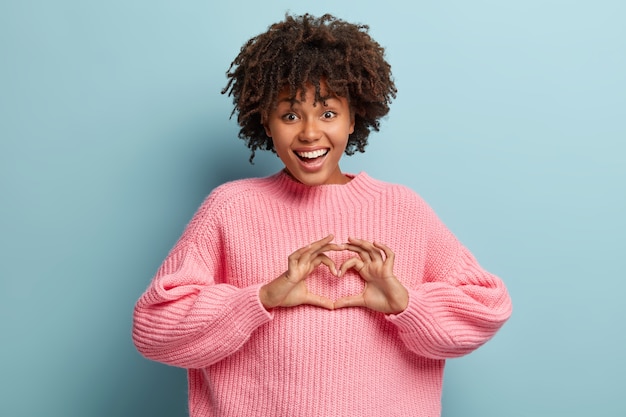 Jonge vrouw met Afro kapsel roze trui dragen