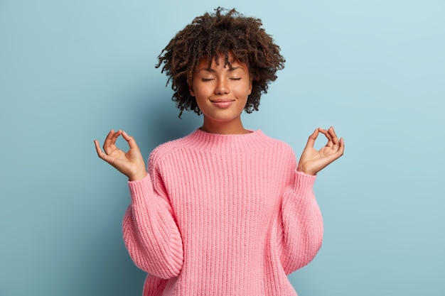 Jonge vrouw met Afro kapsel roze trui dragen