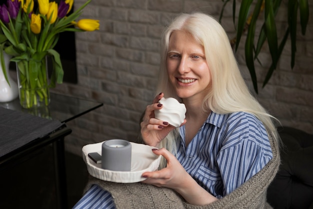 Gratis foto jonge vrouw met albinisme die thuis ontspant met een snack