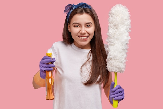 Jonge vrouw met bandana op het hoofd die schoonmakende producten houden