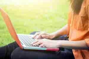 Gratis foto jonge vrouw met behulp van computer op groene glazen in het park.