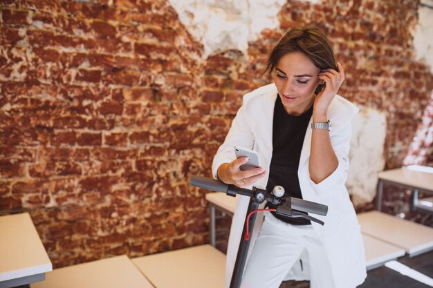 Jonge vrouw met behulp van de telefoon en rijden op scotter