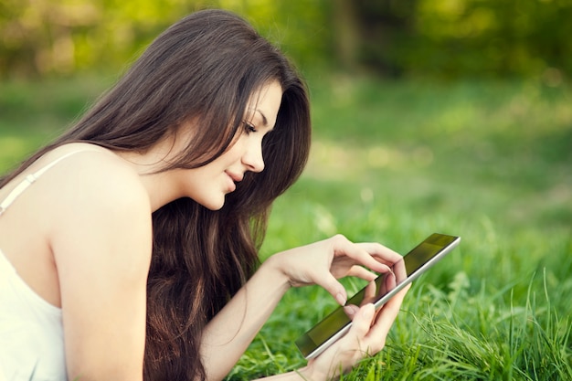 Jonge vrouw met behulp van digitale tablet op weide