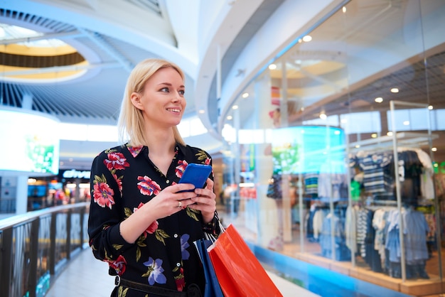 Jonge vrouw met behulp van mobiele telefoon in winkelcentrum