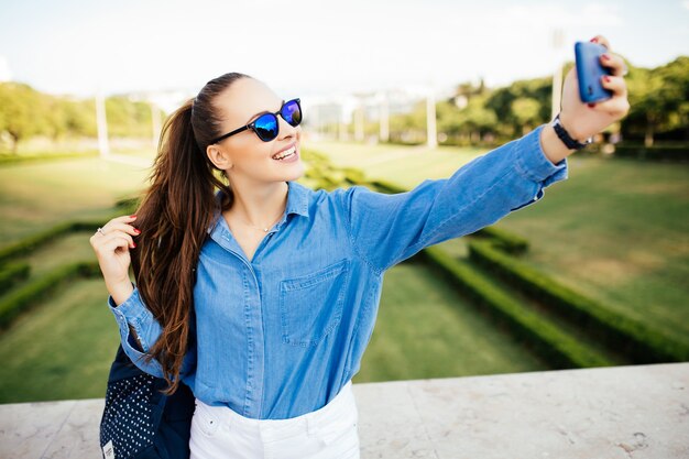Jonge vrouw met behulp van mobiele telefoon selfie te nemen in het park