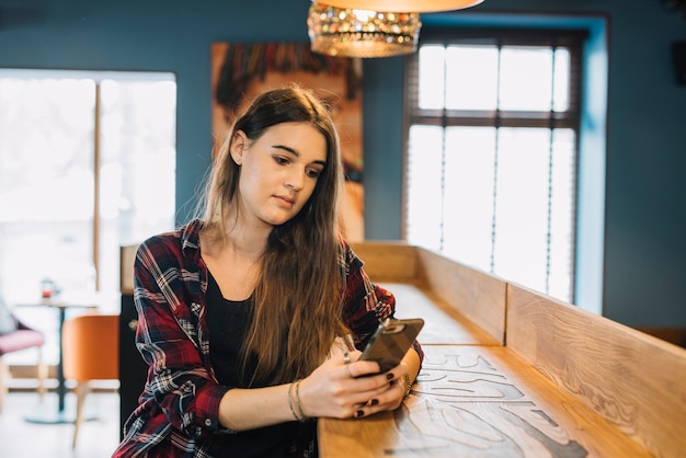 Gratis foto jonge vrouw met behulp van smartphone in café